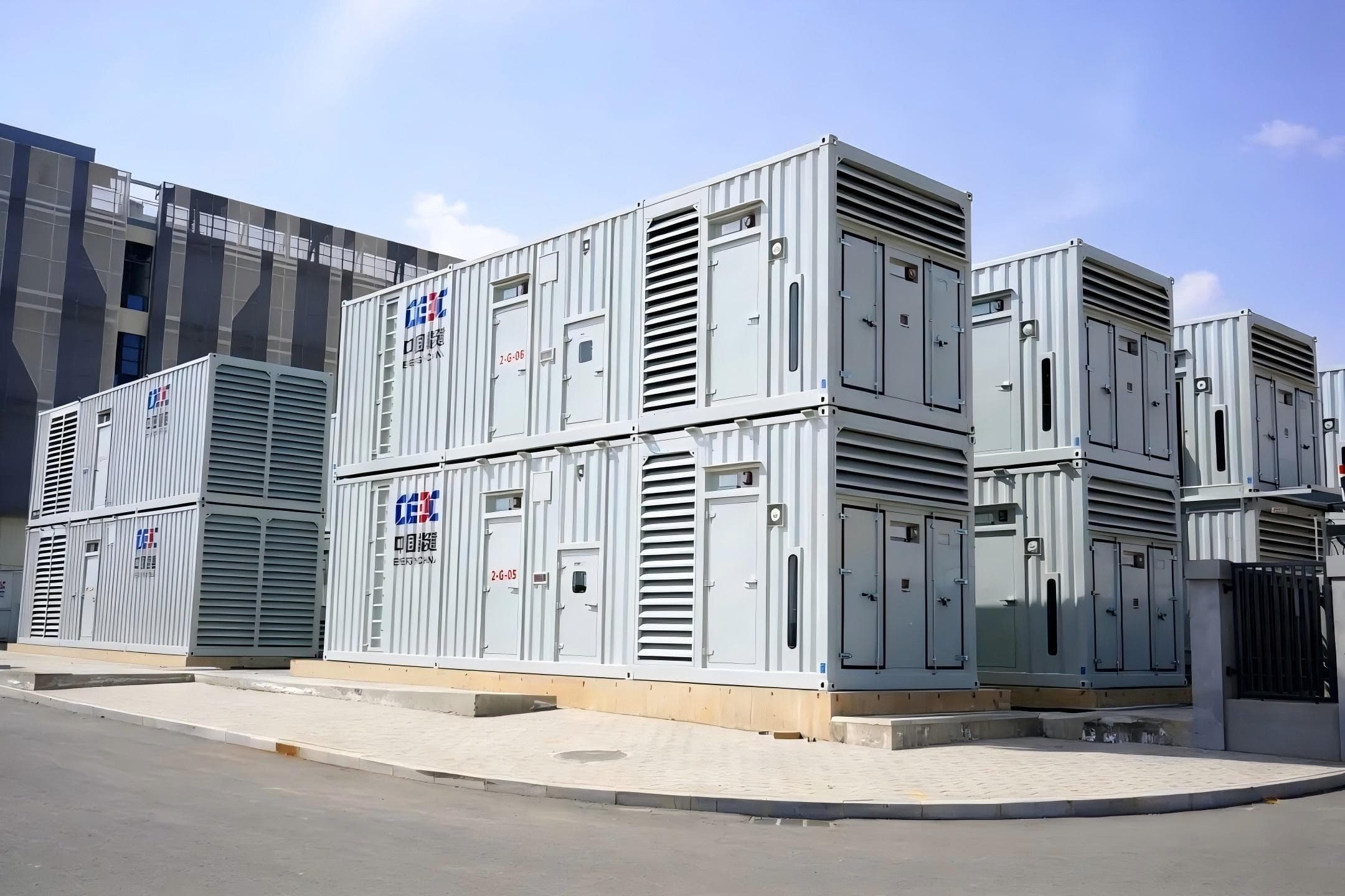 Containerised generator sets staged two-high outside an industrial building