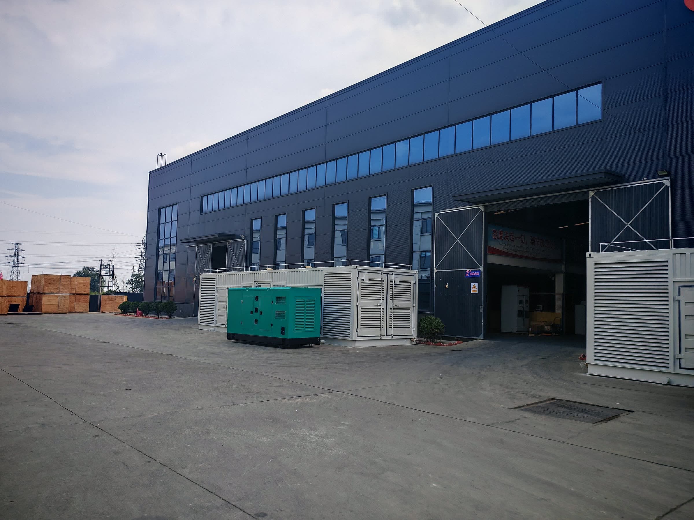 The plant building from the yard, with containerised and canopy sets staged outside the workshop doors