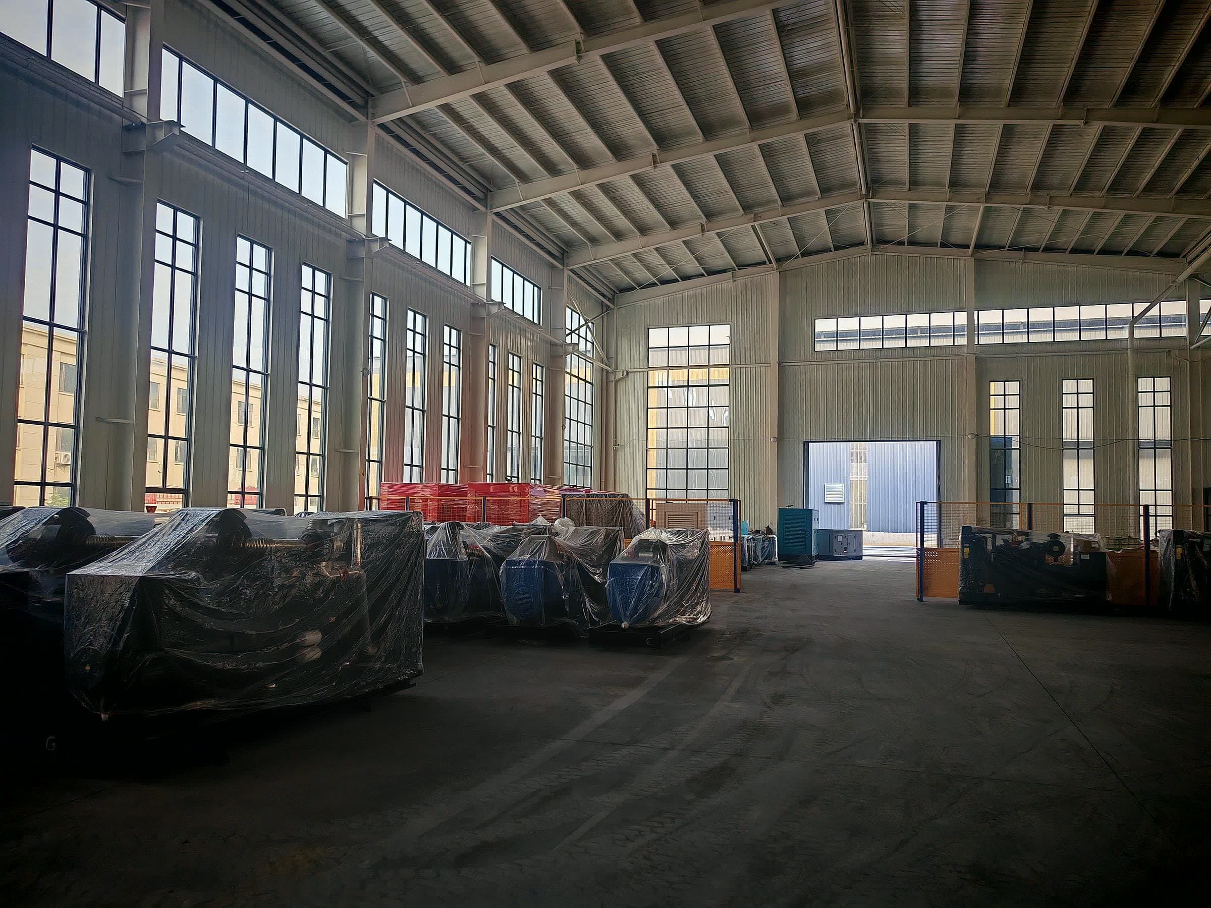 Silent canopy sets wrapped in protective film parked along the wall of a tall workshop