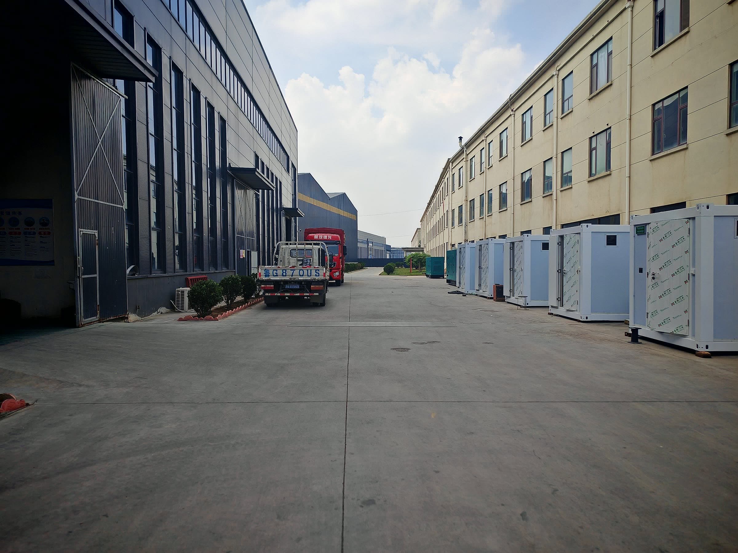 Inside the plant gate: silent generator sets lined up along the workshop road, trucks waiting to load